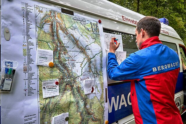 Ein Bergretter trägt Daten in eine Landkarte ein.