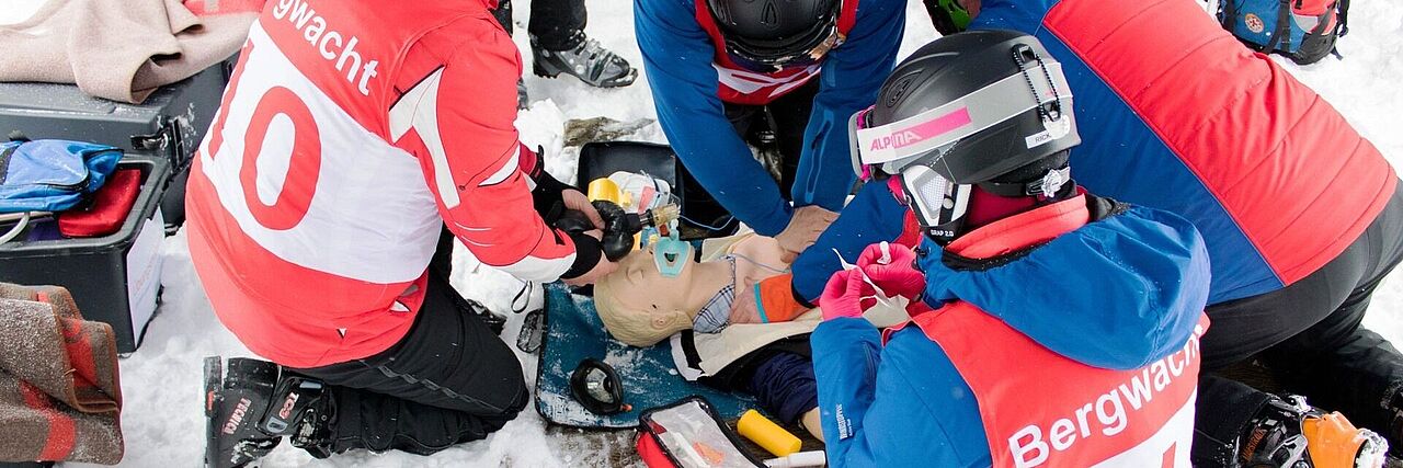 Mehrere Rettende der Bergwacht proben Erste-Hilfe-Maßnahmen an einer Puppe.