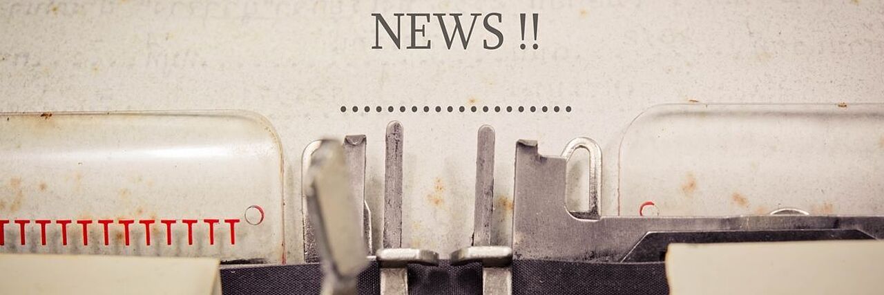 Eine Schreibmaschine ist in Nahaufnahme zu sehen. Auf dem Blatt in der Schreibmaschine steht das englische Wort "News" für "Nachrichten".